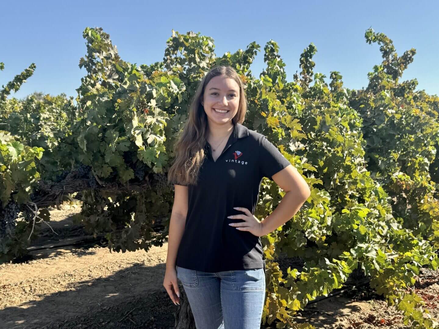 Smiling woman standing in a vineyard.